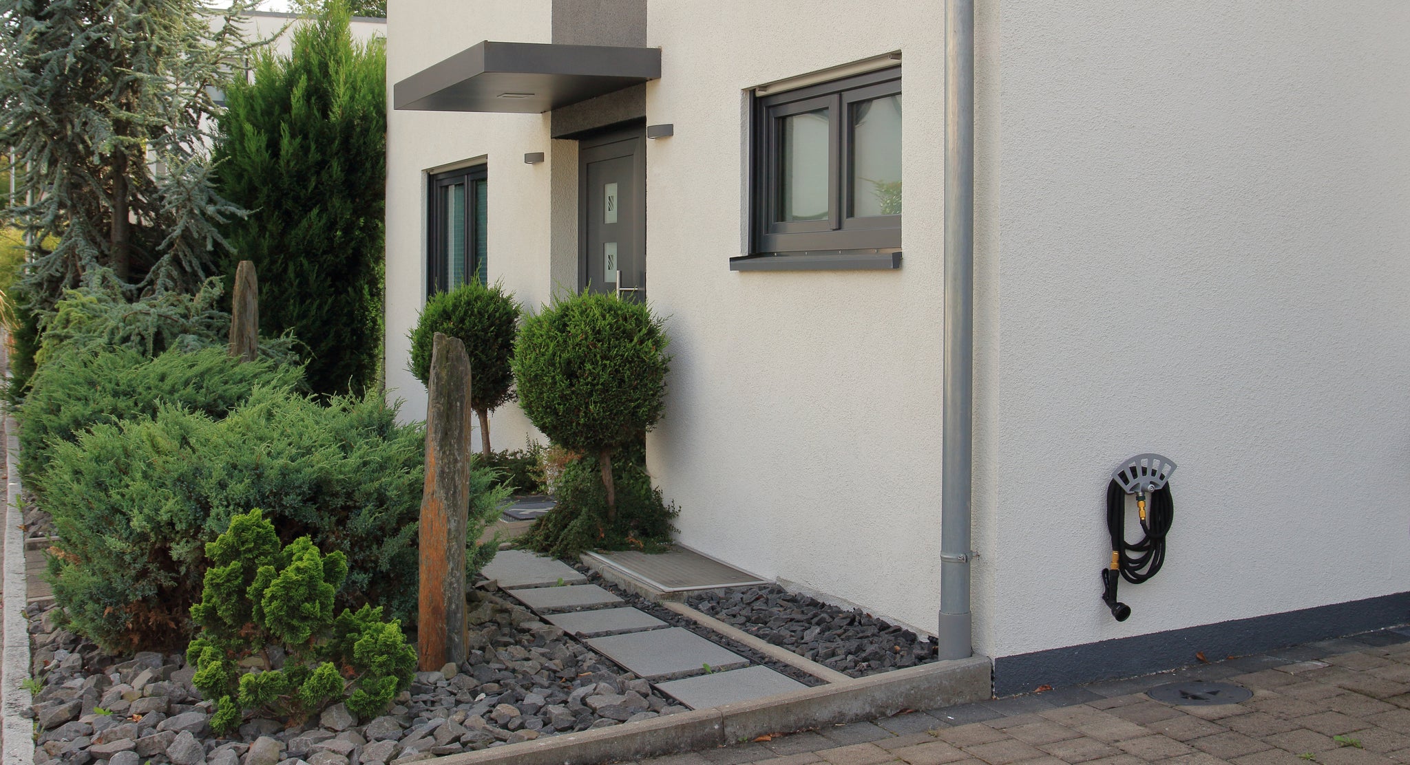 Der Gardenicer Classic fertig montiert am Haus: Platzsparende Aufbewahrung für Gartenschlauch, Spritzbrause und Adapter ohne Bohren in die Fassade.