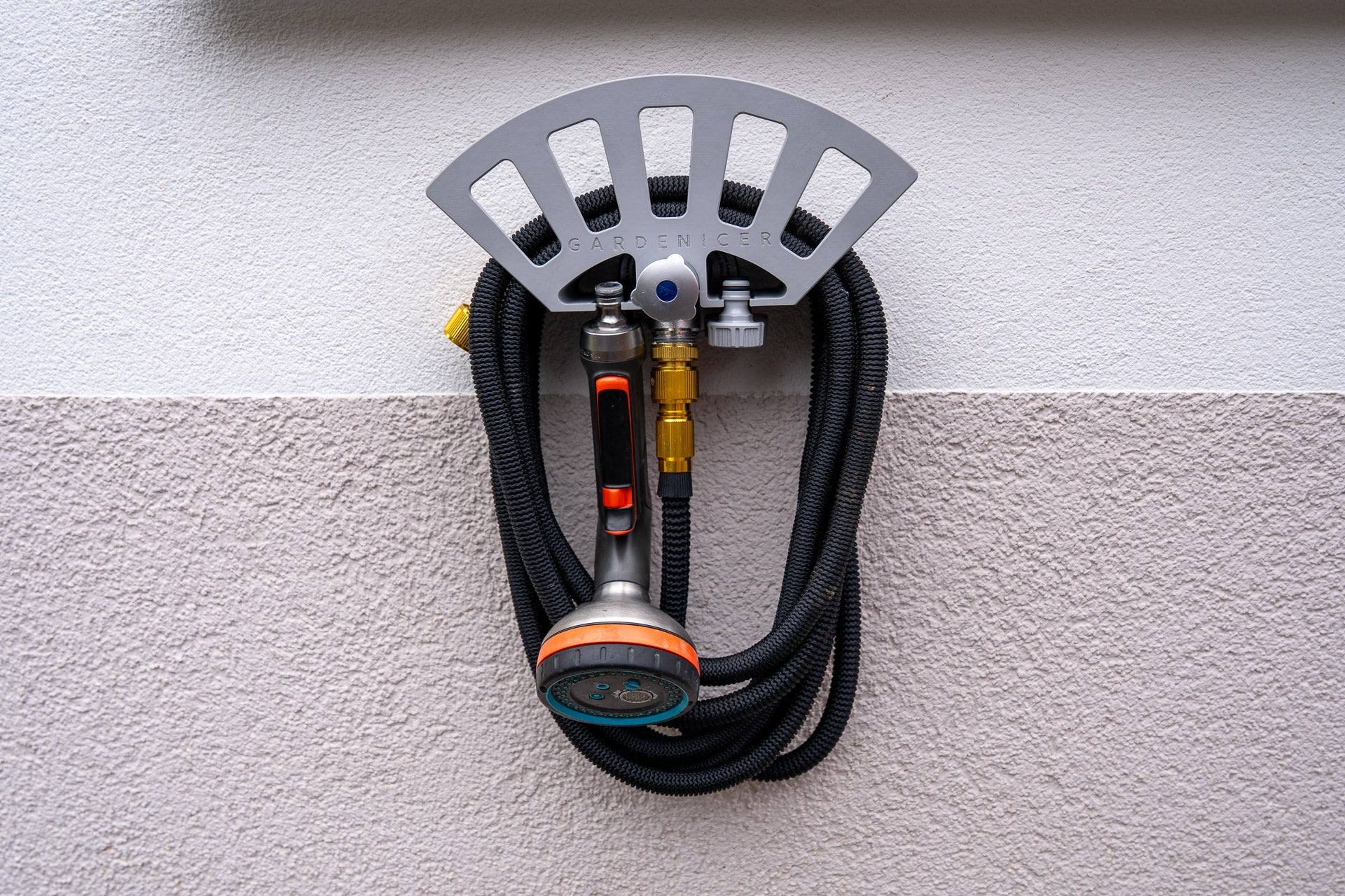 Detailansicht: Gardenicer Classic Schlauchhalter aufgesteckt auf einer kompatiblen Kemper Frosti Außenarmatur, inklusive aufgerolltem Gartenschlauch, Spritzbrause und Adaptern.